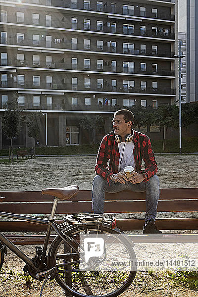 Young man sitting on a bench in the city next to bicycle