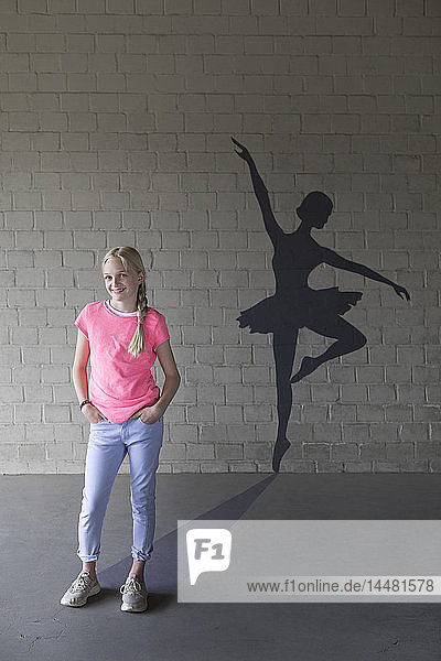 Porträt eines lachenden blonden Mädchens und Schatten einer Ballerina im Hintergrund