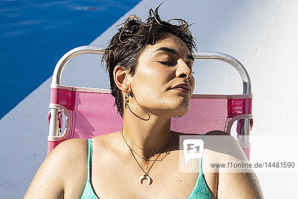 Porträt einer jungen Frau  die sich auf einer Sonnenliege am Swimmingpool entspannt