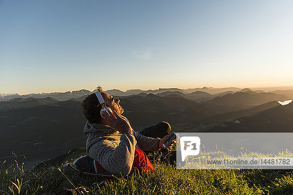 Hiker lying in grass  taking a break and listening music with headphones