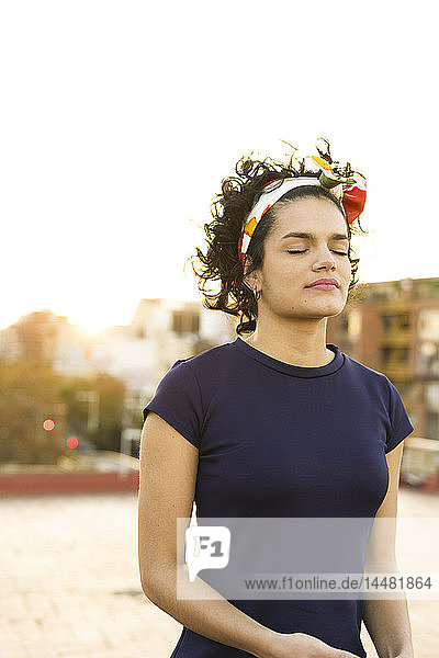 Porträt einer jungen Frau mit geschlossenen Augen in der Stadt bei Sonnenuntergang