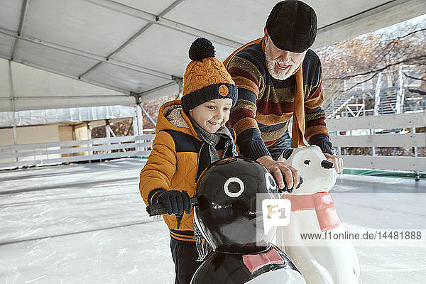 Grossvater und Enkel auf der Eisbahn  Schlittschuhlaufen  mit Eisbärenfigur als Requisite