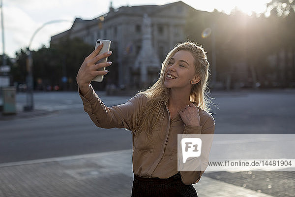 Happy young woman taking a selfie in the city