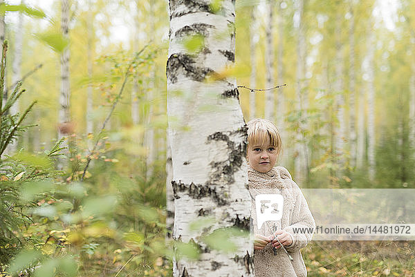 Porträt eines blonden Mädchens beim Spielen im Birkenwald