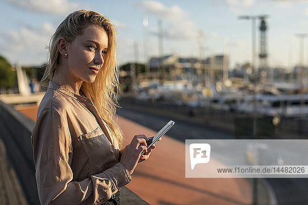 Beautiful young businesswoman with cell phone at the waterfront