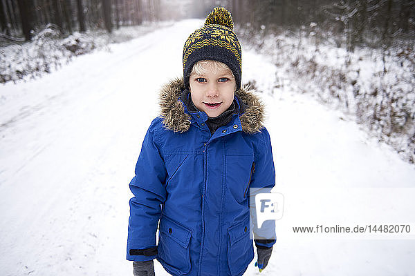 Portrait of little boy enjoying walk in winter forest