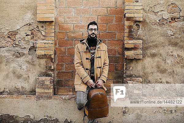 Spain  Igualada  portrait of man with backpack standing at rundown building