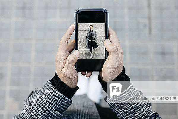 Mann hält Smartphone mit Foto von sich selbst in der Hand  Nahaufnahme