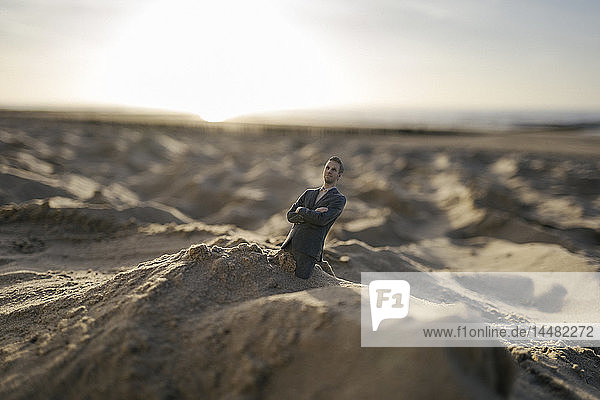 Businessman figurine stuck in sand