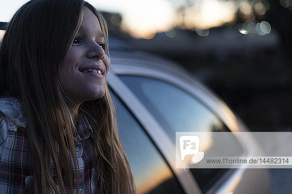 Zufriedenes Mädchen schaut aus dem Autofenster und sieht den Sonnenuntergang