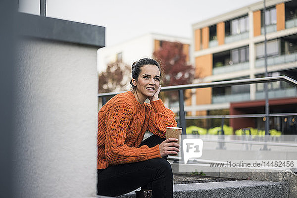 Porträt einer modischen Frau mit Kaffee zum Sitzen auf Stufen im Freien
