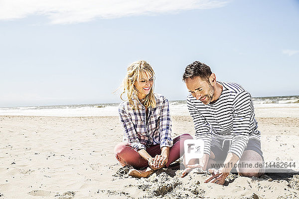 Glückliches Paar sitzt am Strand