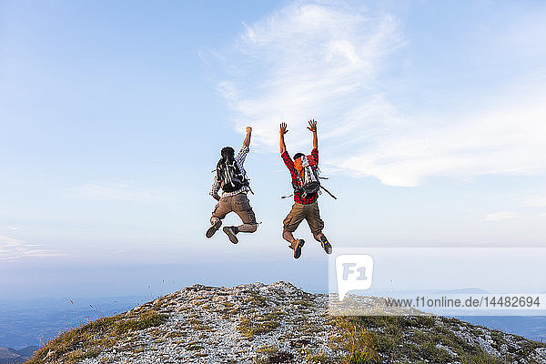 Italien  Monte Nerone  zwei glückliche und erfolgreiche Wanderer  die auf einen Berg springen