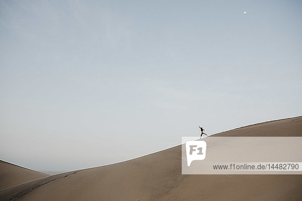 Namibia  Namib  woman running down desert dune