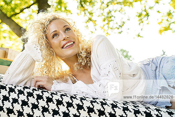 Glückliche junge Frau liegt auf einem Bett im Garten