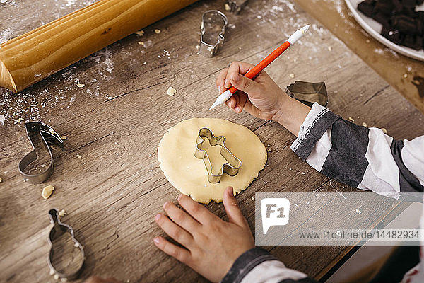 Boy cutting out cookies with tool  partial view