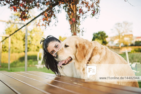 Porträt einer jungen Frau mit ihrem Golden-Retriever-Hund  die sich in einem Park ausruht