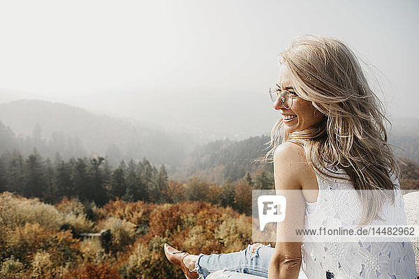Deutschland  Schwarzwald  Sitzenkirch  lächelnde junge Frau im Bergwald sitzend