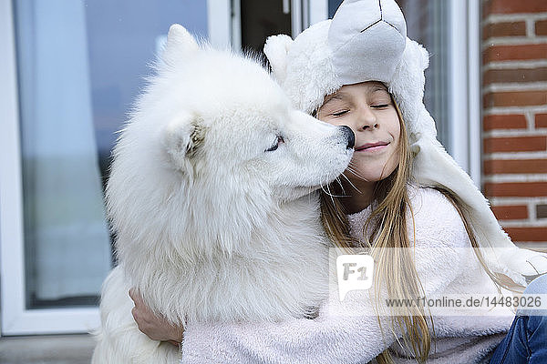 Mädchen umarmt ihren Hund auf der Terrasse