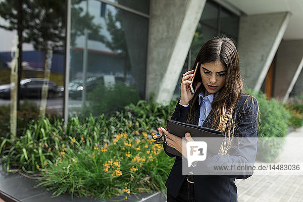 Junge Geschäftsfrau mit Tablet und Handy in der Stadt