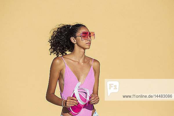 Porträt einer Teenagerin mit Sonnenbrille  geschlossenen Augen  orangefarbener Wand