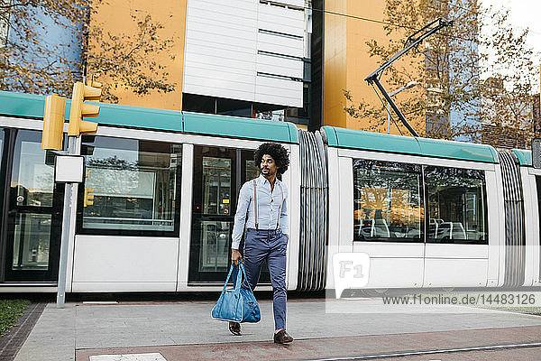 Spanien  Barcelona  Mann mit Tasche überquert die Straße vor einer Straßenbahn