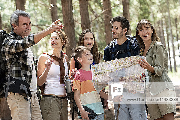 Familie  die im Wald stehend eine Karte liest