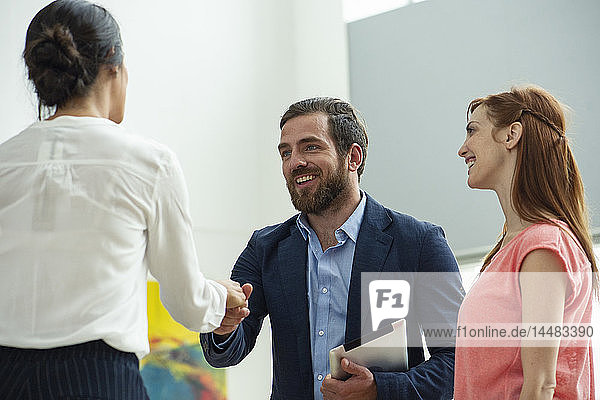 Businessman greeting businesswomen in hotel lobby