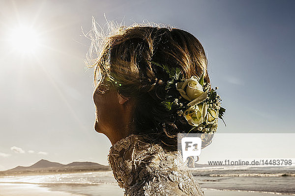 Braut mit Blumen im Haar am sonnigen Meeresstrand