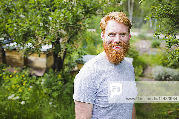 Porträt lächelnder  selbstbewusster Mann mit roten Haaren im Garten
