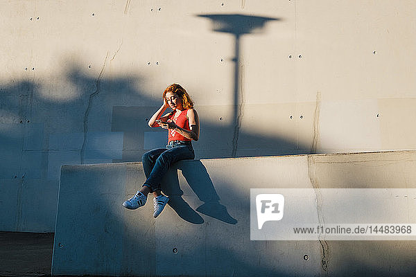 Junge Frau benutzt ihr Smartphone an einer Hauswand