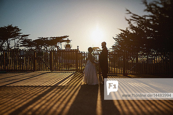Bride and groom standing outside sunny lighthouse  Monterey  Lucas Point  California  USA