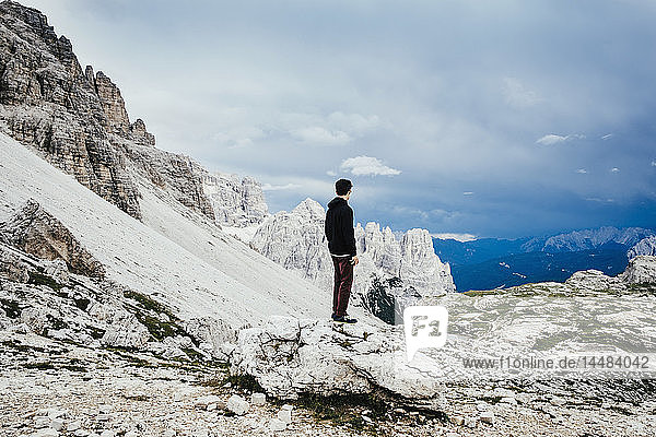 Jugendlicher auf einem Felsen stehend mit Blick auf schroffe Berge  Naturpark Drei Zinnen  Südtirol