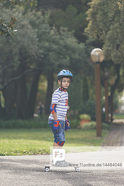Portrait confident boy skateboarding in park