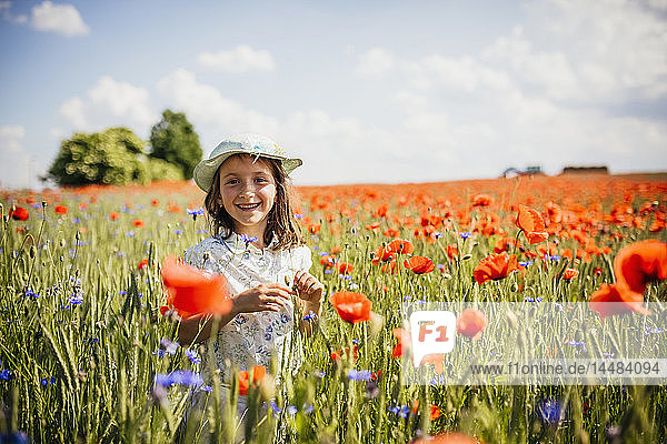 Porträt eines glücklichen  sorglosen Mädchens in einem sonnigen  idyllischen  roten Mohnfeld