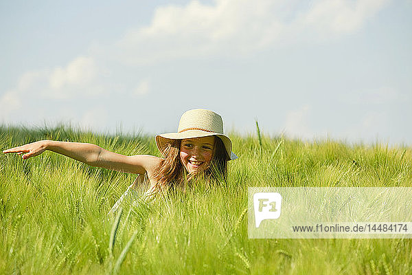 Unbekümmertes  glückliches Mädchen in einem sonnigen  grünen Weizenfeld