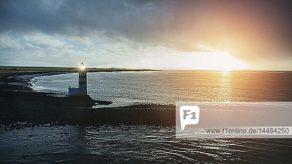 Idyllischer Sonnenuntergang über Meer und altem Leuchtturm  Reykjanesbaer  Island