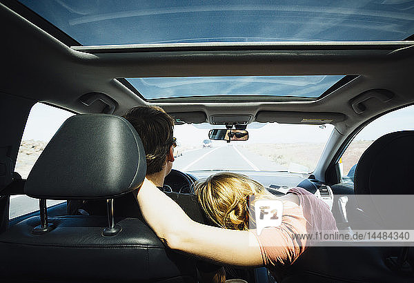 Zärtliches Paar fährt in sonnigem Auto