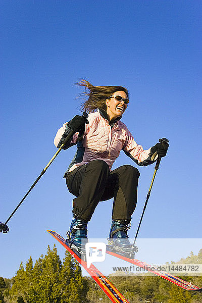 Junge Frau in der Luft springt auf Skiern bergab Dixie National Forest Utah Winter