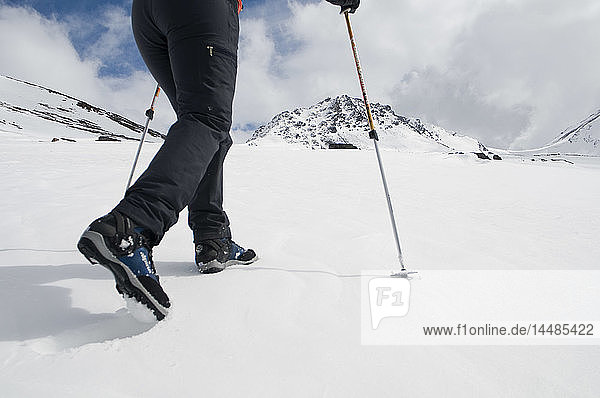 Closeup of a hiker´s legs walking on snow with ski poles in the Chugach Mountains  Southcentral  Alaska