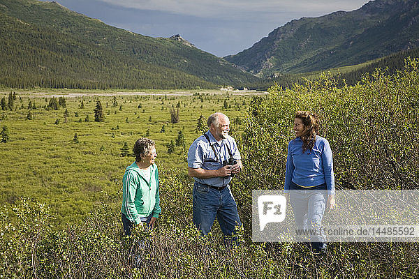 Mature couple and middle age woman hike on tundra in the Sanctuary river area of Denali National Park  Alaska