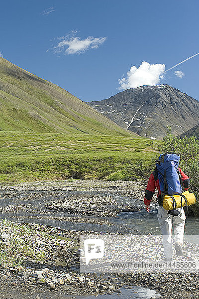 Man backpacking along the Chandalar River in the Brooks Range during Summer in Arctic Alaska