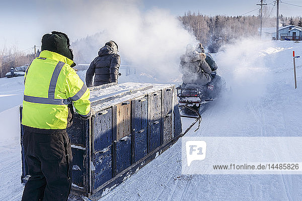 Volunteers take a sled load of dropped dogs towards the airport at the Ruby checkpoint during Iditarod 2015