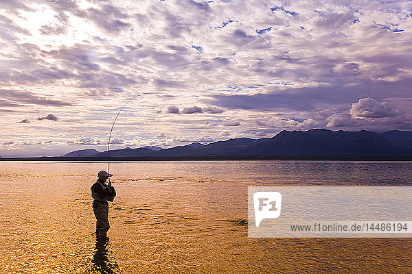 Person beim Fliegenfischen bei Sonnenuntergang im Lake Clark des Lake Clark National Park in der Nähe der Mündung des Tanalian River in Southcentral Alaska im Sommer