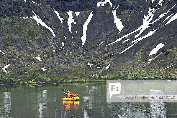 Eine Frau in einem kleinen Floß wirft am Surprise Lake im Aniakchak National Monument and Preserve im Südwesten Alaskas nach Seesaiblingen.