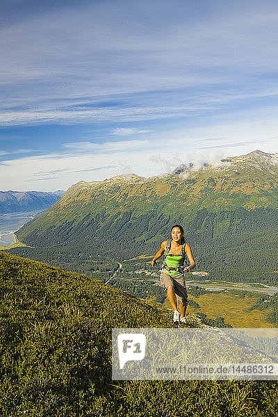 Junge erwachsene hispanische Frau beim Wandern auf dem Gipfel des Berges Alyeska mit Blick auf die Chugach Mountains und das Girdwood Valley in Süd-Zentral-Alaska