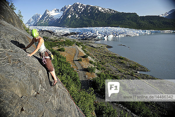 Woman rock climbing with Spencer Glacier in the background  Chugach National Forest  Kenai Peninsula  Southcentral Alaska  Summer