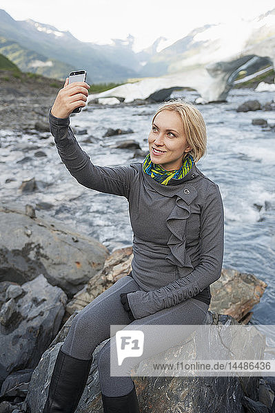 Frau benutzt ein Smartphone für ein Selfie im Portage Valley  Southcentral Alaska