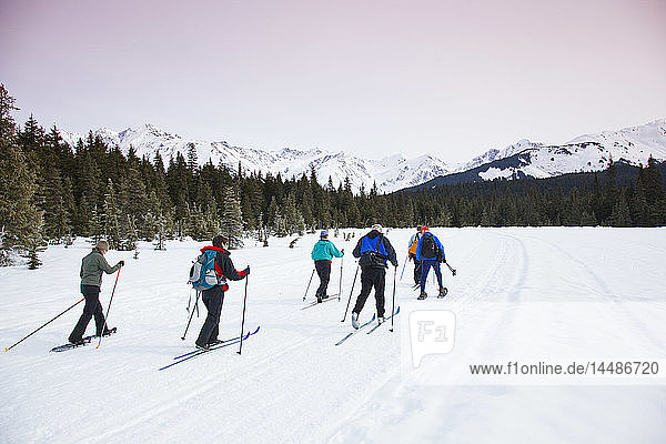 A group of friends cross country ski and snowshoe on the multi-use Moose Meadow trail near the Alyeska Hotel in Girdwood  Alaska  Spring