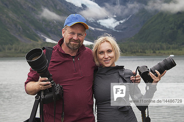 Two photographers pose with their cameras along Portage Lake  Southcentral Alaska